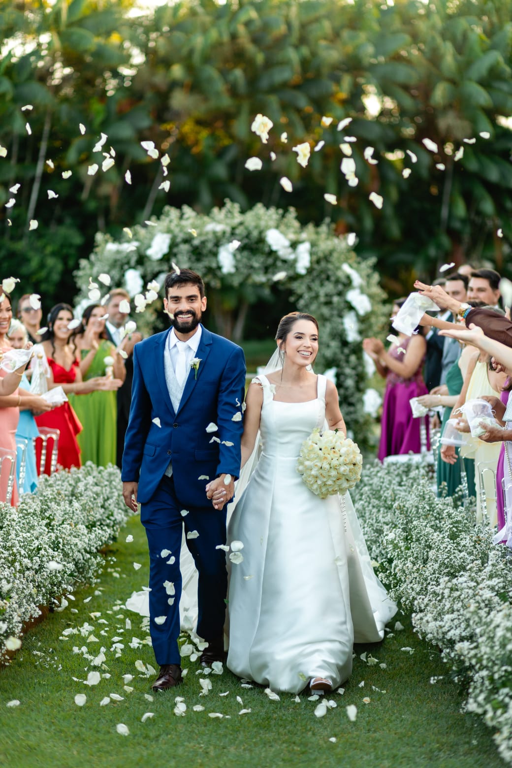 Saída dos noivos celebrando sob pétalas de flores naturais